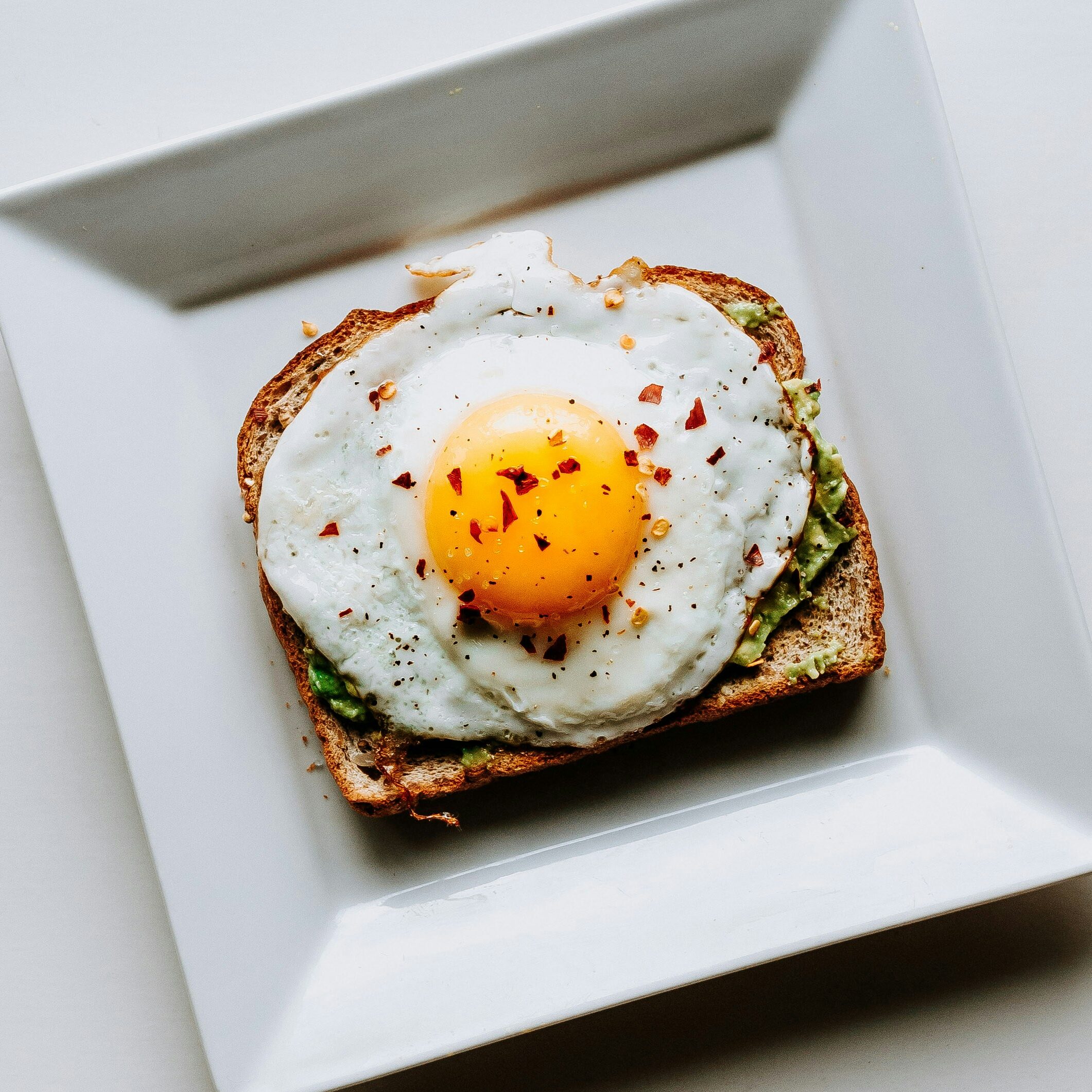 Toast med avokado och stekt ägg toppat med chiliflakes