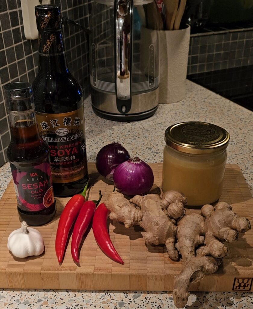 Koreansk marinad Skärbräda med ingredienser till marinad. Sojasås, sesamolja, chili, ingefära, rödlök, vitlök, och honung.