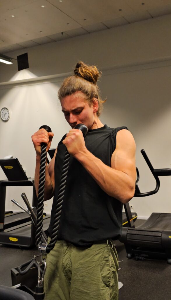 Rope curls Biceps curls med ett svart rep, visar armarna