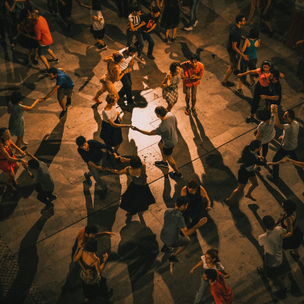 En stor grupp människor som dansar tillsammans på ett öppet torg.