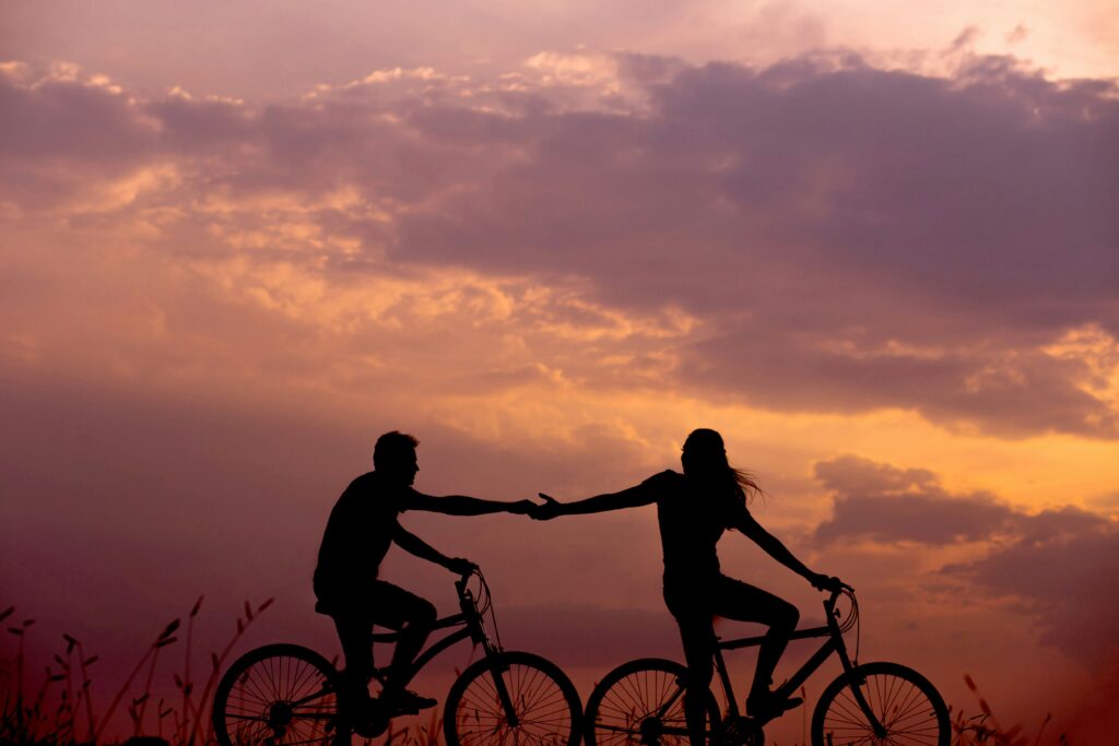 Cykel sunset En man och en kvinna håller hand när de cyklar i solnedgången.