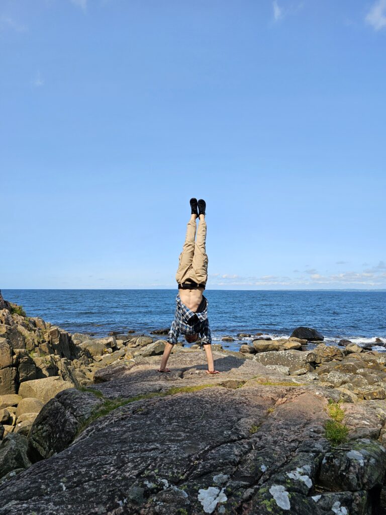 Man som står på händer framför havet
